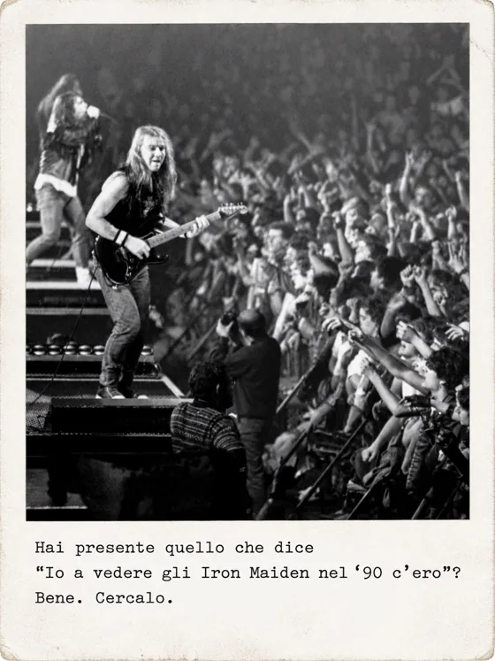 Un chitarrista sul palco davanti a una folla di braccia alzate, con un fotografo sotto il palco.